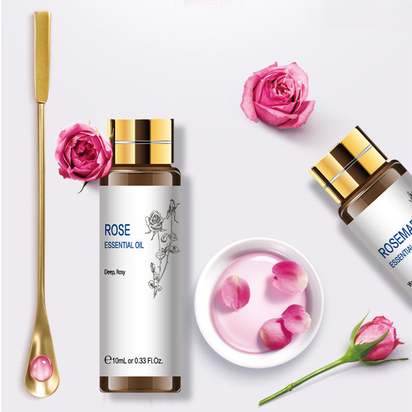 Rose essential oil bottle 10ml with fresh roses and petals, featuring a gold applicator for skincare and aromatherapy.