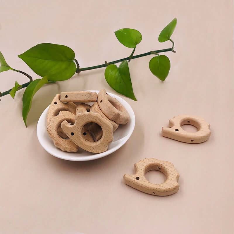 Wooden baby teething toys in various animal shapes on a bowl, made from natural beech wood, perfect for bite and grind.