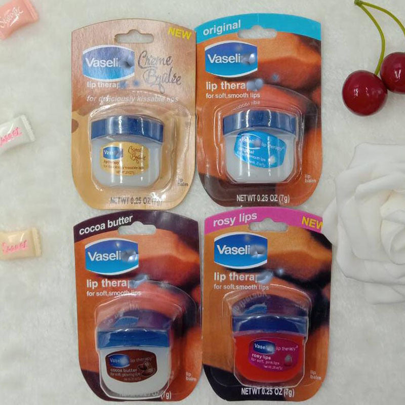 Four types of Vaseline Lip Therapy displayed on a soft surface, featuring original, rosy lips, cocoa butter, and crème brulee variations.