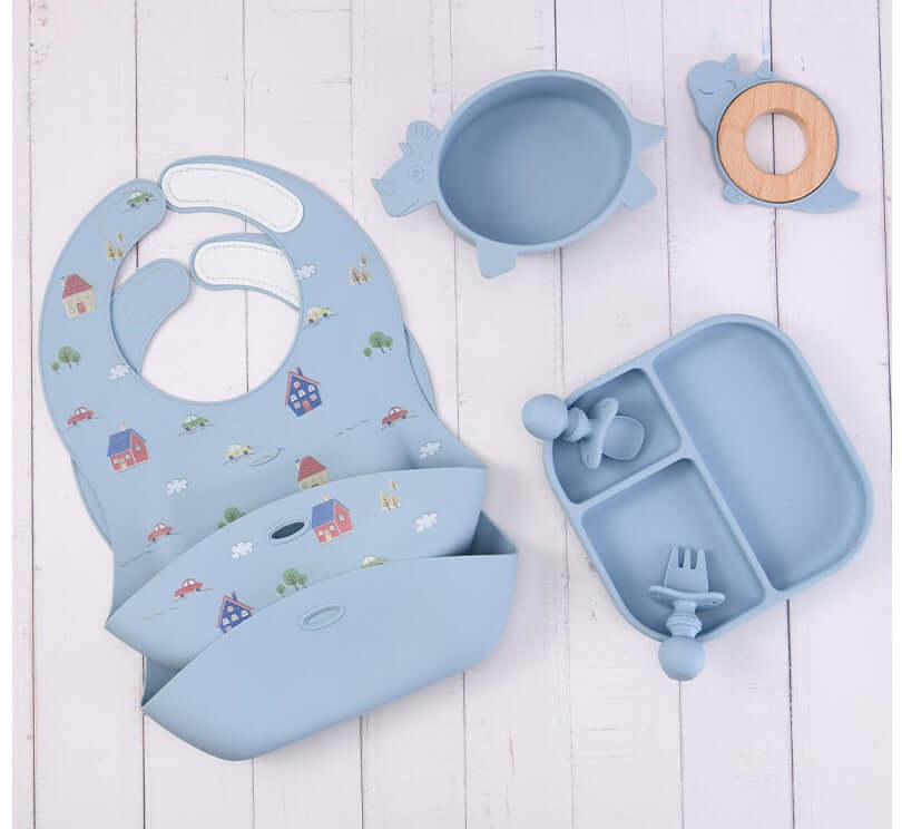 Silicone baby tableware set including bibs, plate, bowl, spoon, and fork in light blue color with cute designs for baby food accessories.