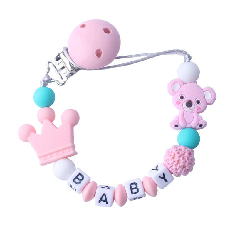 Pink silicone and wood pacifier clip with baby beads, crown, and teddy bear charm.