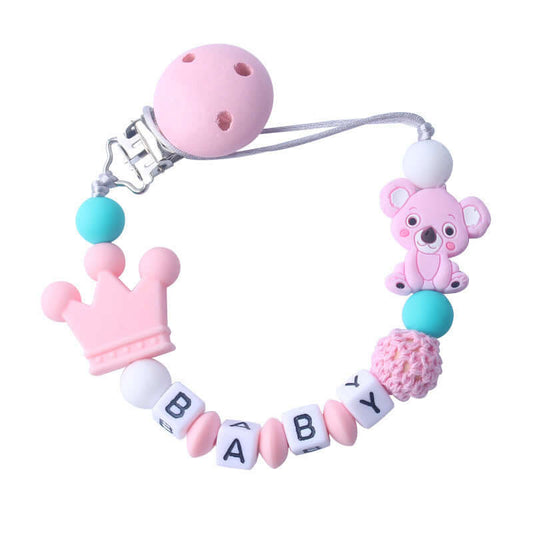 Pink silicone and wood pacifier clip with baby beads, crown, and teddy bear charm.