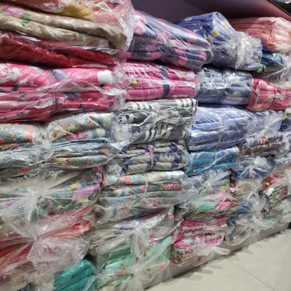 Stacks of colorful packaged bedding sets on display in a store, featuring various patterns and vibrant designs.