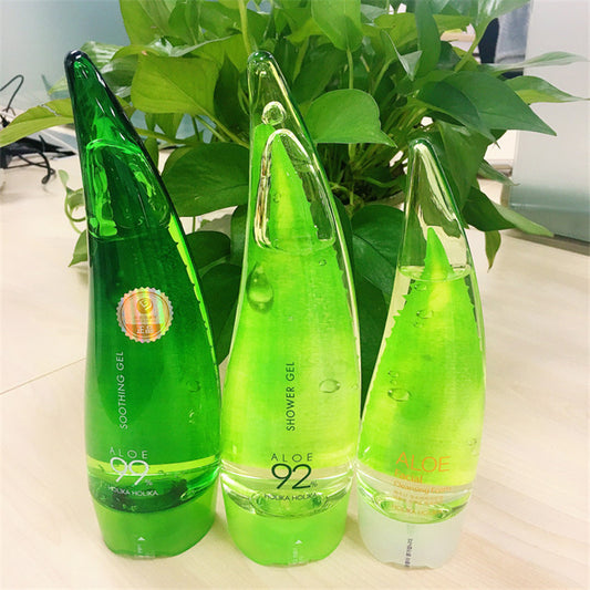 Aloe vera gel bottles on a table with green plants in the background, showcasing natural moisturizing skincare products.