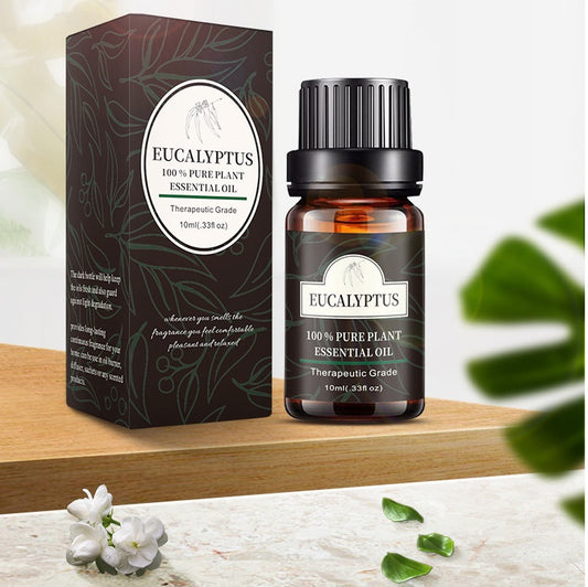 Eucalyptus essential oil bottle with packaging on wooden surface, surrounded by green leaves and small white flowers.